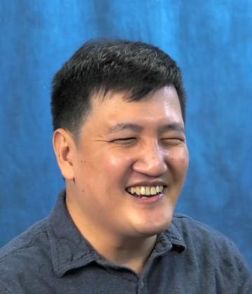 Thumbnail image of Chi Kim with a warm smile, sitting in front of a blue backdrop.